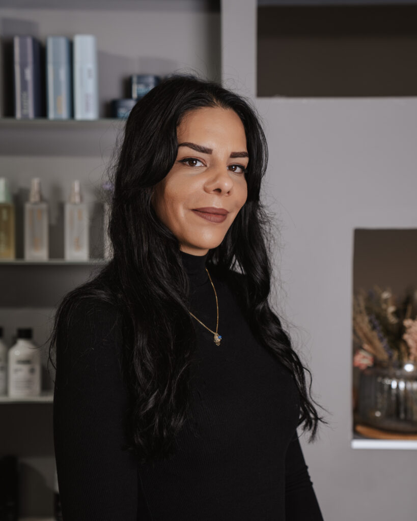 yasmin 2024 Yasmin im Porträt: Mit Herz, Schere und Stil Yasmin, Friseurin bei Helena Conzen Hairdesign, lächelnd im Salon in Bochum.
