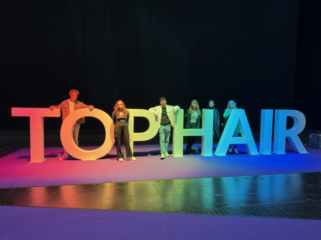 Team von Helena Conzen Hairdesign vor dem TopHair 2025 Logo in Düsseldorf – gemeinsamer Messebesuch mit Fokus auf Weiterbildung, Trends und Teamspirit.
