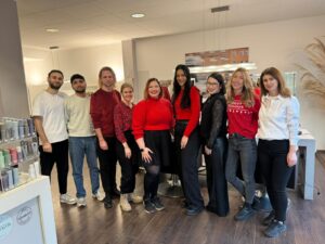 WhatsApp Image 2025 12 22 at 08.58.27 Wir lieben Haare Teammitglieder stehen lächelnd im Salonbereich und posieren gemeinsam für ein Foto; helle, moderne Einrichtung im Hintergrund.