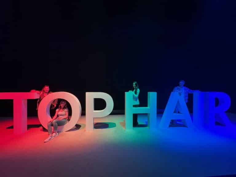 Ein Teil des Teams von Helena Conzen Hairdesign auf der TopHair 2026 in Düsseldorf vor dem beleuchteten TOP HAIR Schriftzug.