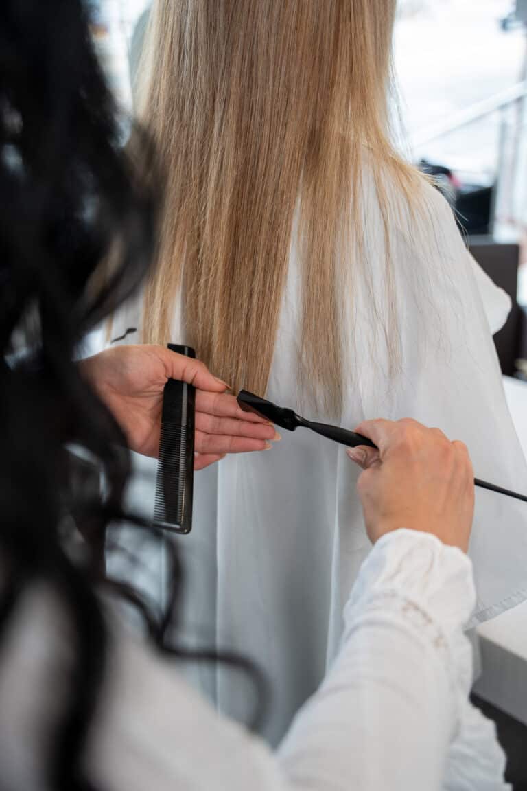 Friseurin führt einen Calligraphy Cut an blondem Haar im Salon durch