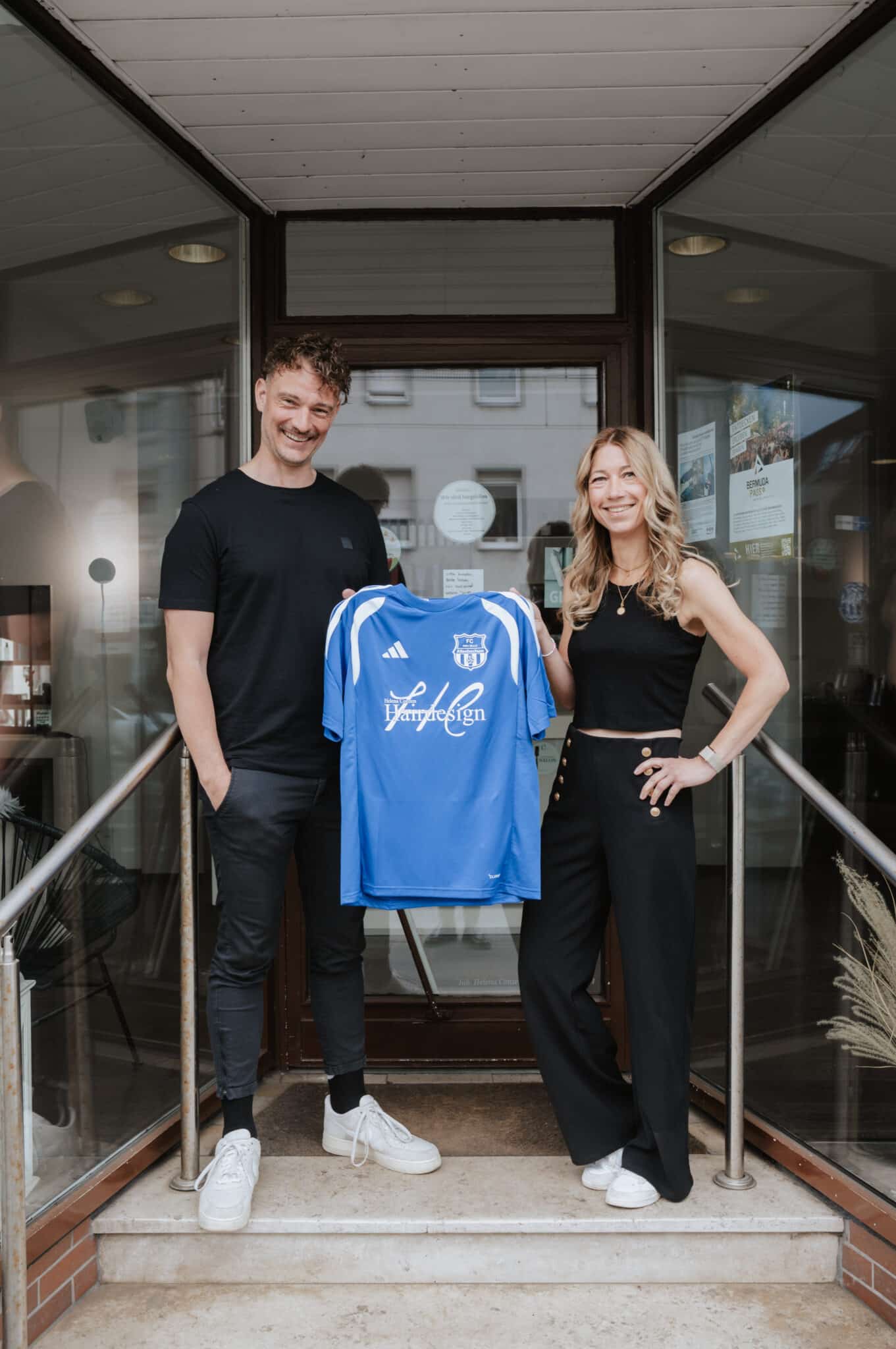 helena conzen hairdesign als trikotsponsor des fc altenbochum Helena Conzen Hairdesign wird Trikotsponsor der Jugend des FC Altenbochum Helena und Dustin von Helena Conzen Hairdesign halten ein blaues Trikot des FC Altenbochum mit Salonlogo vor dem Friseursalon in Bochum.